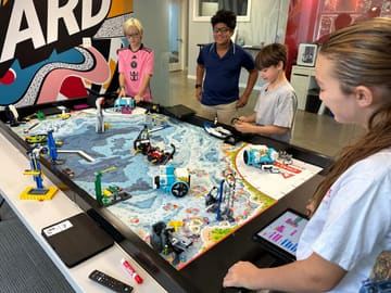 A student and her teammates programming a robot on a themed competition table