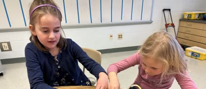 Two homeschool students programming a robot build together during a daytime class