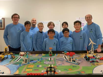 An UP Robotics FIRST LEGO League team working around a competition table